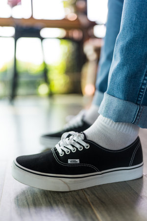 Bangkok, Thailand - December 1, 2024 : The Vans black and white sneakers worn on the legs of a teenager. Vans is a manufacturer of skateboarding shoes.のeditorial素材