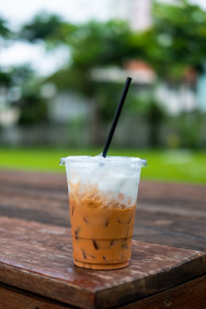 Iced Thai tea in the plastic cup after drink finished on wood table at outdoor cafeの写真素材