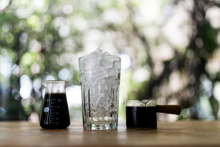 Making of ice coffee, shot of espresso, cool water and ice in glass ready to making black coffee on wood tableの写真素材