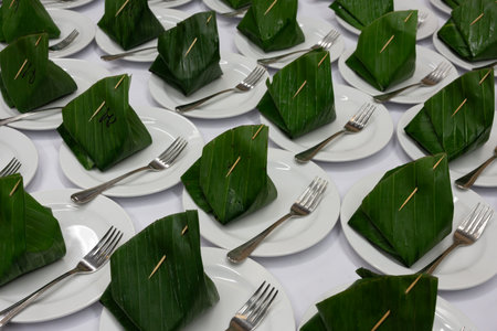 Thai dessert, Sticky rice with steamed custard, wrapped in banana leaves on ceramic saucer prepared for served breaks between seminarsの写真素材