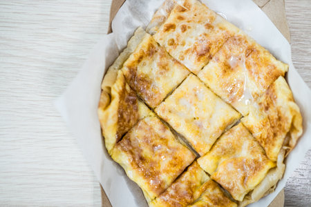 Roti with egg and sweetened condensed milk, cut into square pieces, placed on white paper.の写真素材