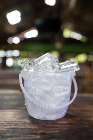 Ice cube in a transparent plastic bucket on a table. Close upの写真素材