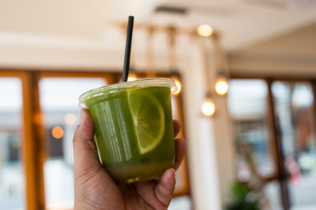 Delicious lemon green tea drinks in plastic cup on hand at cafe
