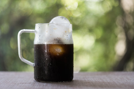 Iced americano coffee in glass with handle against nature backgroundの写真素材