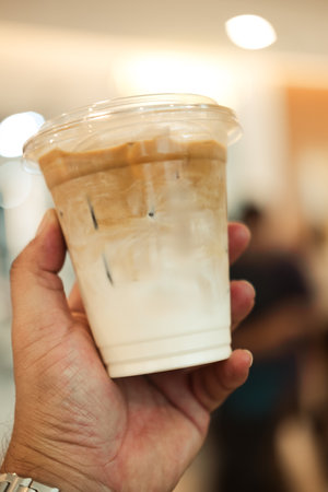 Close up of hand holding iced coffee latte in plasticの写真素材