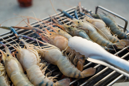 Man use tong fresh river shrimp on the grid for grilled. Close upの写真素材
