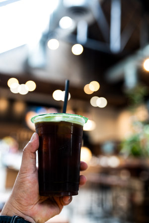 Hand holding a glass of iced black coffee at coffee shop.の写真素材