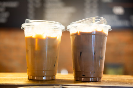 Two takeaway glasses filled with cold coffee with ice cubes on tableの写真素材