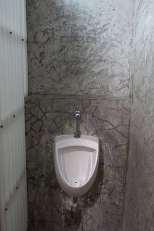Closeup of one white urinals in men bathroom on loft cement wall design of white ceramic urinals for men in toilet room. Loft styleの写真素材