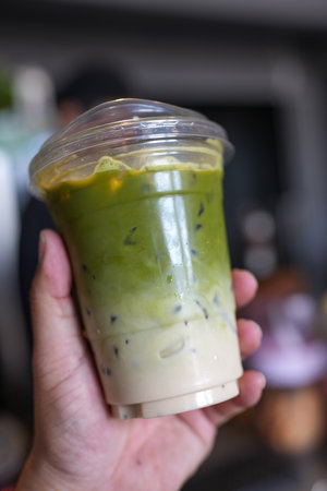 Iced matcha green tea latte in plastic glass on handの写真素材