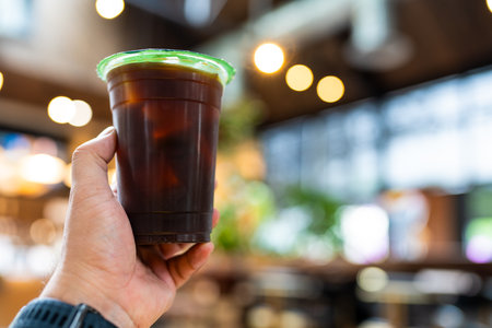 Hand holding iced black coffee or americano coffee