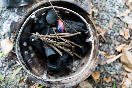 Put dry stick on charcoal in a stove igniting fire for cooking at camping. Top viewの写真素材