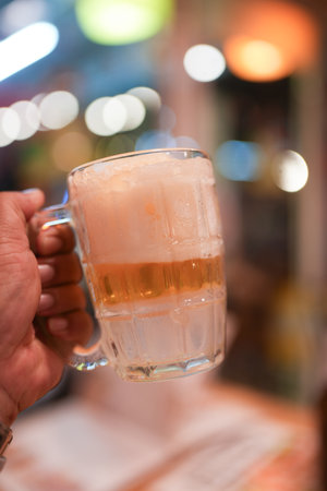Enjoying a frost cold beer in a frozen mug at a casual gathering during dinner foodの写真素材