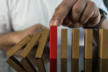 man stops domino falling. Risk management concept. Successful strong business and problem solving. Reliable leader. Stop the destructive processes. Strategy development. Debt restructuringの写真素材