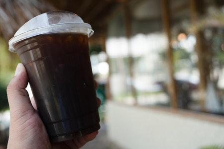 Iced black coffee in takeaway cup in man handの写真素材