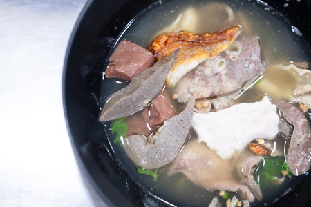 Boiled pork entrails and blood jelly soup in black bowl. Thai food