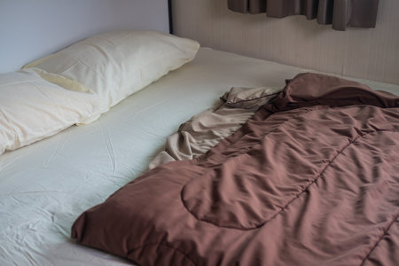 A bed with a brown blanket in homeの写真素材