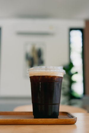 Close up of take away plastic cup of iced black coffee americano on wooden tableの写真素材