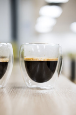 Double wall glass cup with hot coffee on tableの写真素材