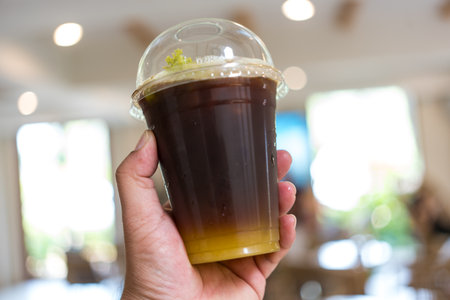 Iced americano black coffee mix of orange juice on hand with blur backgroundの写真素材