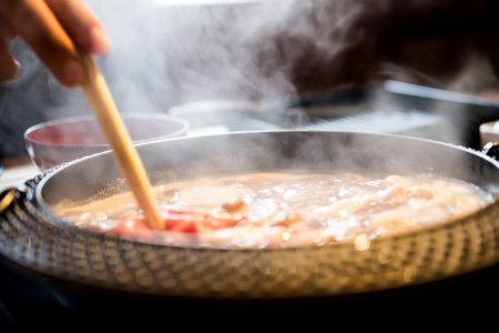 Holding sliced pork using chopsticks on hot pot with smoke for Japanese hot pot also known as Shabu Shabu or Sukiyaki is Japanese style.の写真素材