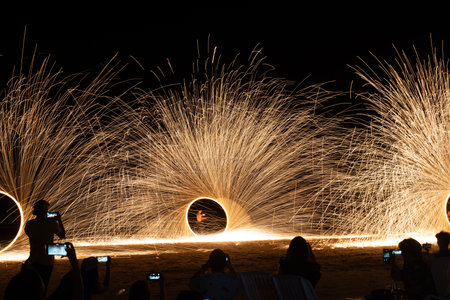 Dancer show swinging the fire of steel wool on the beach in party near bar and restaurant in...