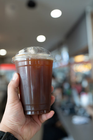 Takeaway cup of iced black coffee on hand. Close upの写真素材