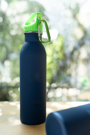 Full length blue water bottle against a nature background on wood tableの写真素材