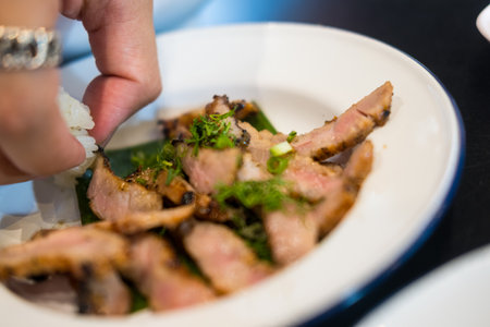 Man use hand pick up of a slices medium rare grilled beef eating with sticky rice. Thai foodの写真素材