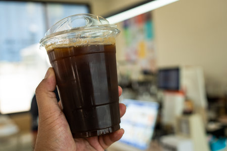 Close up shot of iced americano coffee in hand and anti plastic strawの写真素材