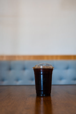 A take away plastic cup of iced black coffee on wood tableの写真素材