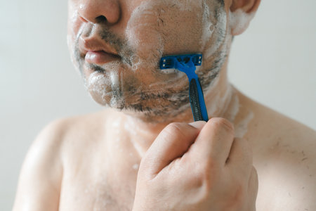 Man shaving beard in bathroom, capturing daily morning grooming routine, personal hygiene, and...