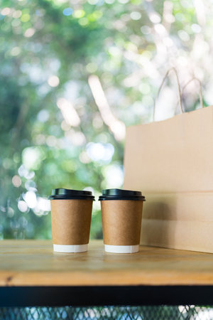 Paper coffee cup with black lid and brown paper bag for design template of an eco friendly productの写真素材
