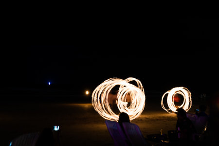 Fire artists doing show on the beach in Thailand. Light painting and long exposure picture to form trails.の写真素材