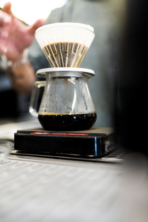A skilled barista prepares filtered drip coffee in a coffee shop.の写真素材