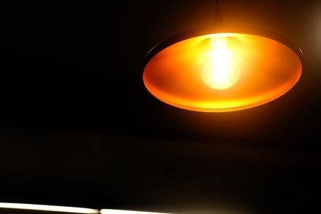 Round pendant lights hang from the ceiling and cast soft orange lightの写真素材