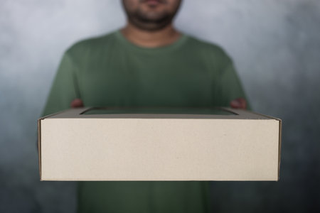 Hand holding a blank cardboard box for business delivery. Parcel box delivery to the customer