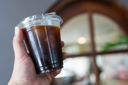 Cold black coffee with ice in take away plastic cup on man handの写真素材