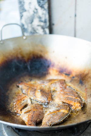 Frying crisp tilapia fish on hot oil panの写真素材