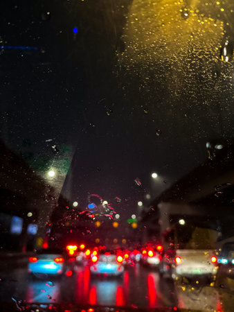 On rainy nights, the rain-covered window glass reflects the city lights and forms colorful abstract patternsの写真素材