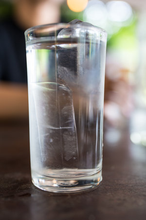 Close up a glass of fresh water with ice cubes on the wooden table ready to drink at dinner meal time, drinking water at dinner meal time at restaurantの写真素材
