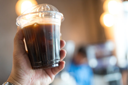 Cold Brew coffee drinks in people hands on blurred cafe background