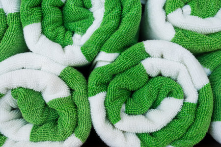Freshly rolled green and white towels lie neatly folded. Rolled beach towels textureの写真素材