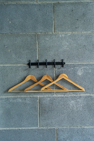 Three minimalist wooden hangers on a rack. Decoration loft style, uneven brick wall