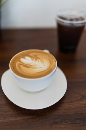 Cozy coffee shop scene with latte art and ice black coffee background on wood table