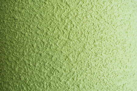 A rough, painted green wall with a distinctive patina, showing subtle layers of color and textureの写真素材