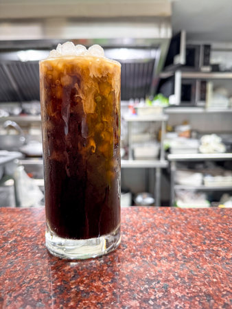 A glass of Thai black coffee with cream poured overの写真素材