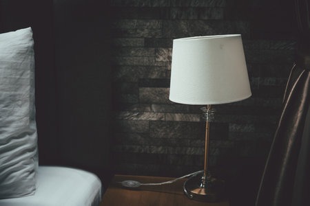 Classic table lamp standing on the bedside table with white pillowの写真素材