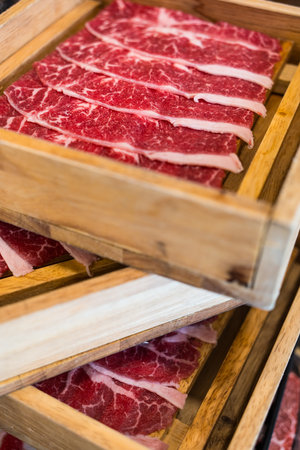 Rare sliced wagyu beef for sukiyaki in wood trayの写真素材