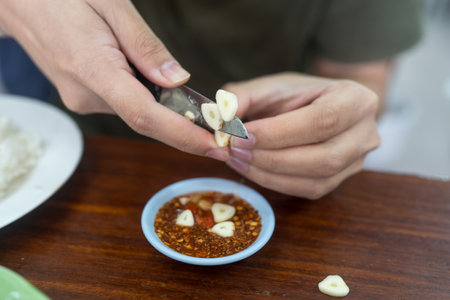 Hand use knife peeling garlic and cut put in to chili sauce. Close upの写真素材